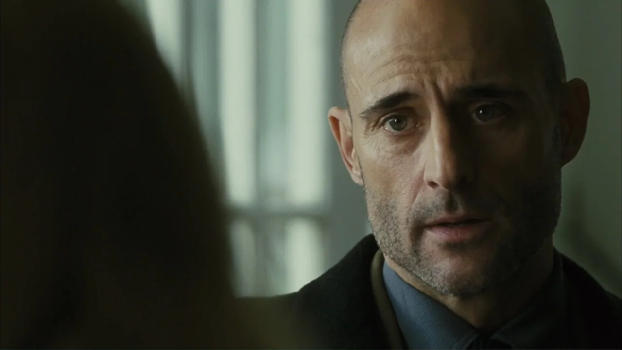 Before I Go to Sleep (2014) movie still: closeup — An interior space features a blurred background with a light-filled window. A bald man wearing a…