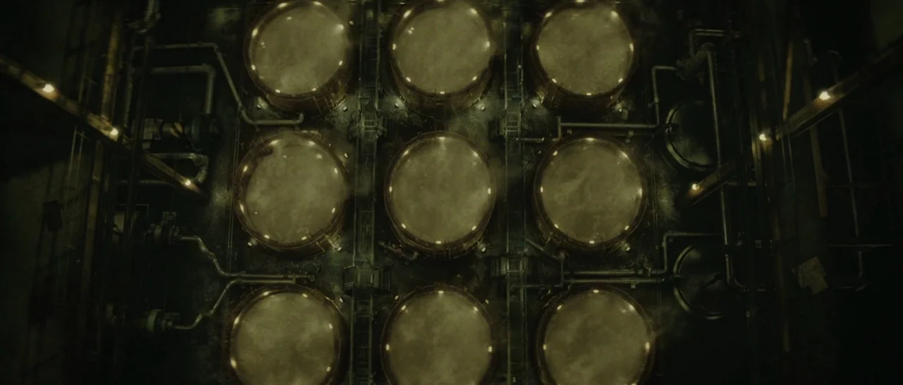 Suicide Squad (2016) movie still: establishing — A high-angle view of nine large industrial vats arranged in a grid pattern. Pipes and metal…