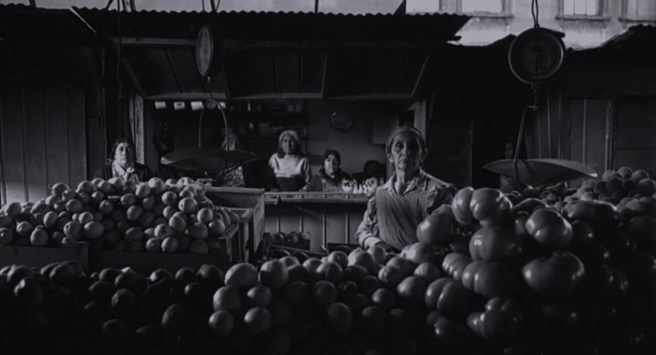 The Motorcycle Diaries (2004) movie still: medium — An indoor produce stall features wooden counters piled high with mounds of various fruits. A…