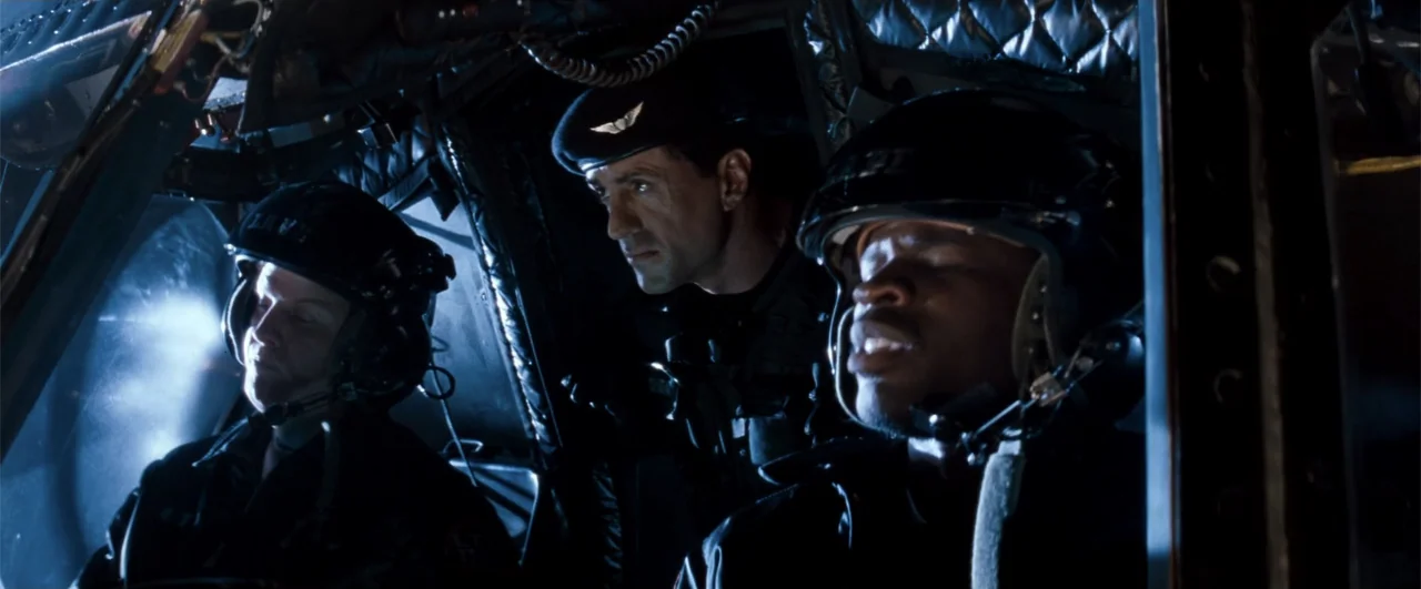 Demolition Man (1993) movie still: medium — The cramped interior of a helicopter cockpit at night features dark metallic surfaces. Three individuals…