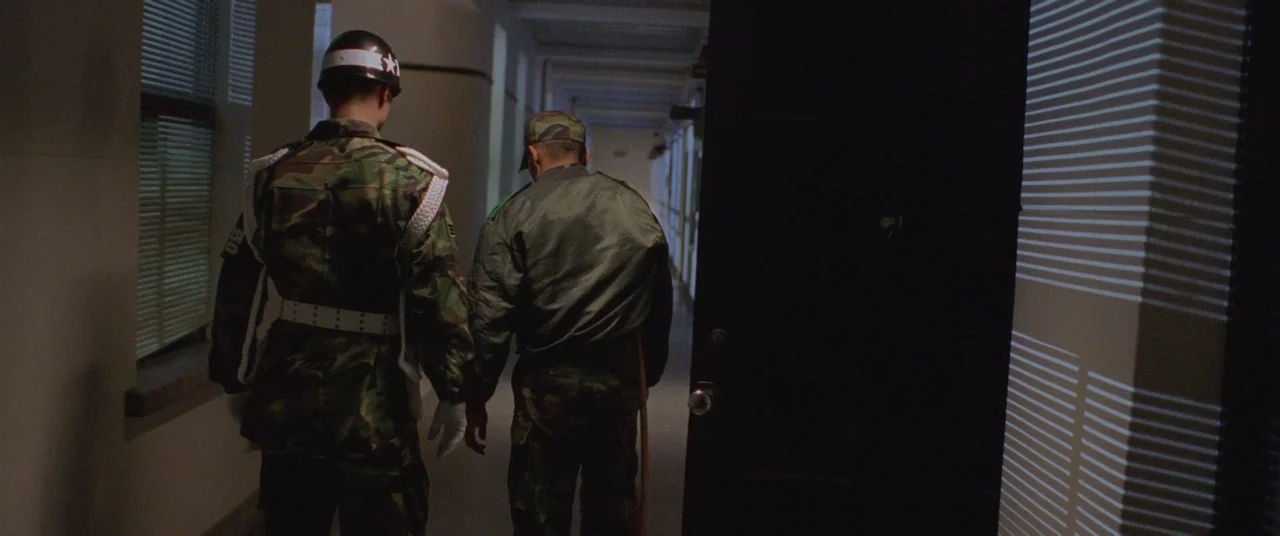 Joint Security Area (2000) movie still: fullbody — A long, dimly lit institutional hallway features vertical walls and windows with closed…
