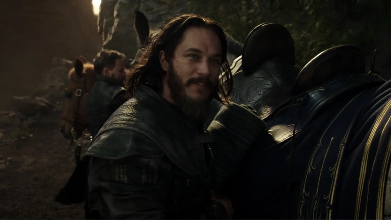 Warcraft (2016) movie still: medium — A rocky mountain trail with dim light filters through nearby large stone cliffs. A bearded man in leather…