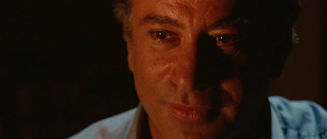 Death Walks On High Heels (1971) movie still: closeup — A man's face is illuminated in a dark interior space. He gazes directly toward the viewer.
