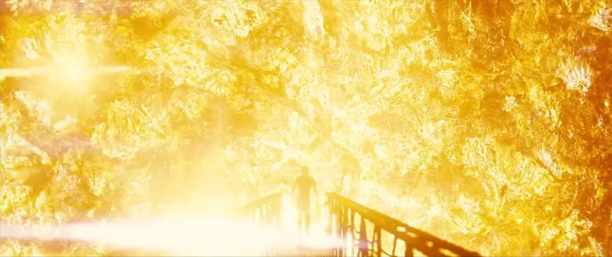 Sunshine movie still: wide — A dark figure stands on a narrow bridge surrounded by an intense golden field. The surroundings appear like a bright,…