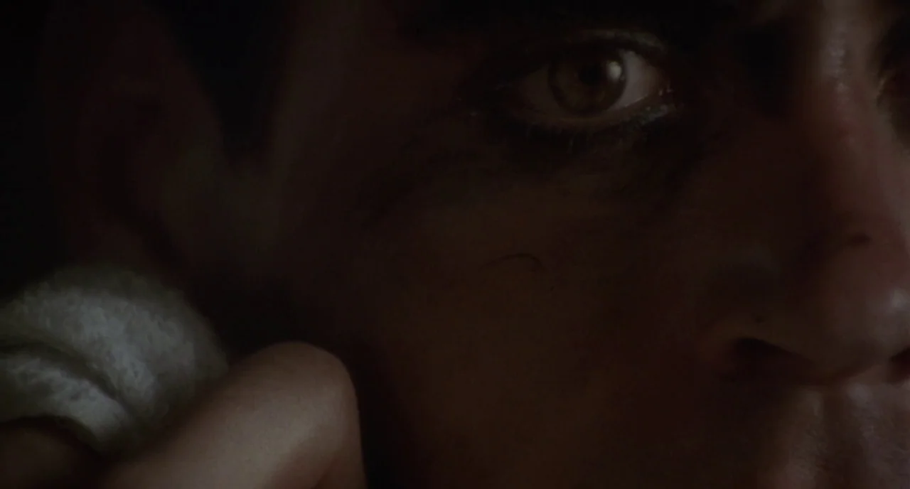 Chaplin (1992) movie still: closeup — A close-up view of a man's face partially obscured by deep, dark shadows. A white towel is pressed against his…