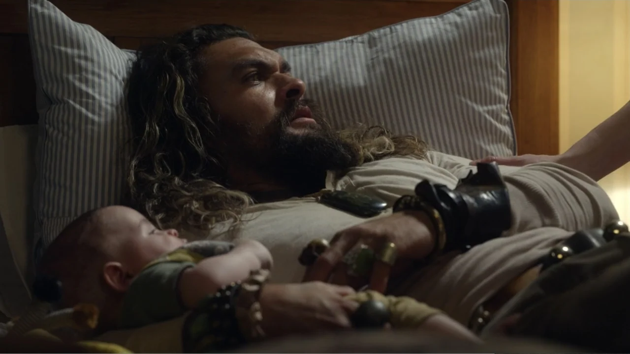 Aquaman and the Lost Kingdom (2023) movie still: medium — A cozy room features a striped pillow on a wooden bed frame. A bearded man rests while…