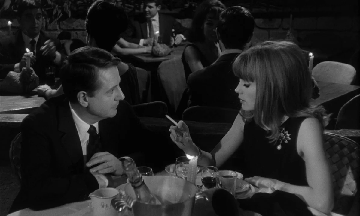 La Peau Douce (The Soft Skin) (1964) movie still: medium — A dimly lit dining area with multiple tables and patrons visible in the background. A man…
