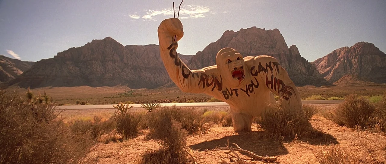 Fear and Loathing In Las Vegas (1998) movie still: wide — A tan, concrete gorilla statue stands in a vast, sun-drenched desert plain with red…