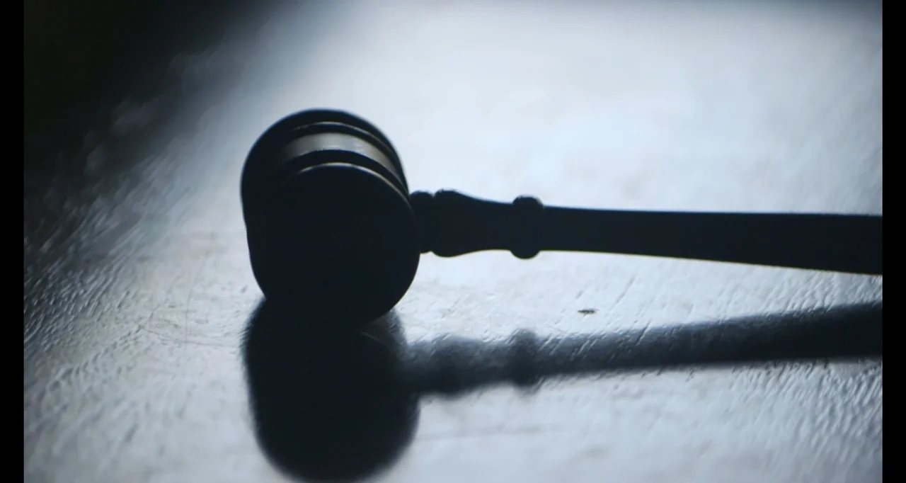 Hunted by My Husband: The Untold Story of the DC Sniper (2025) movie still: closeup — A close-up view shows a wooden judge's gavel lying on a dark…
