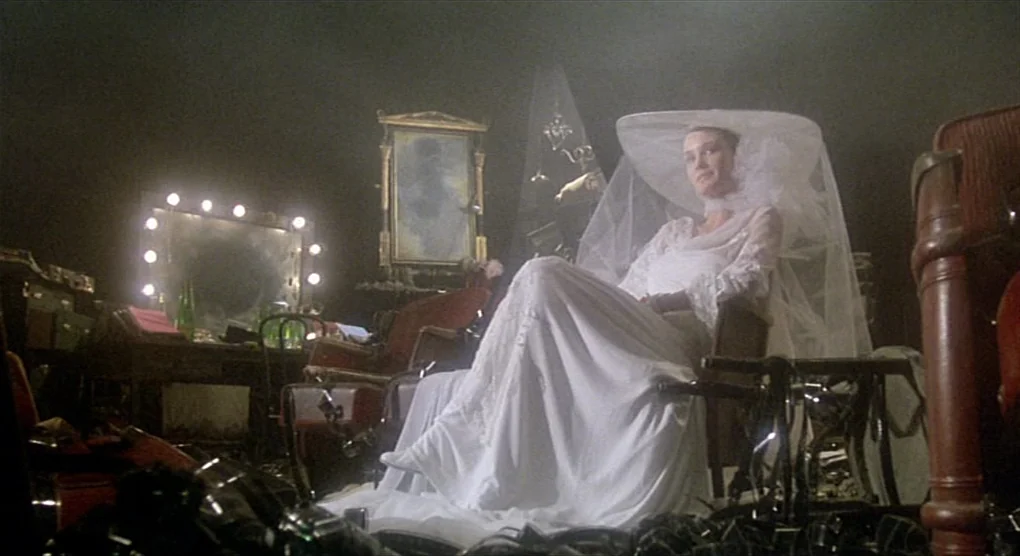 All That Jazz (1979) movie still: fullbody — A dimly lit, cluttered room features an ornate vanity mirror and antique furniture pieces. A woman in a…
