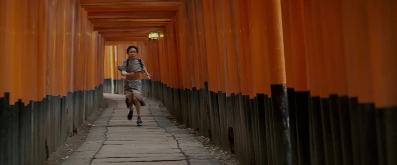 Memoirs of a Geisha (2005) movie still: fullbody — A long, narrow passage lined on both sides by rows of orange torii gates. A young girl in…