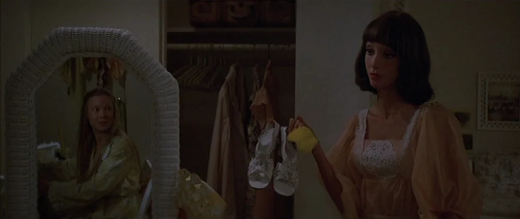 3 Women (1977) movie still: medium — A cluttered dressing area features a wicker-framed mirror and an open closet. One woman stands facing the…
