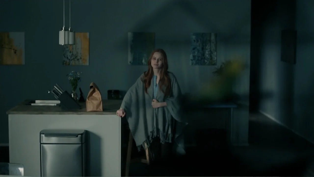 Sightless (2017) movie still: medium — A modern kitchen features a stone island with a paper bag and trash bin. A woman with long red hair wearing a…