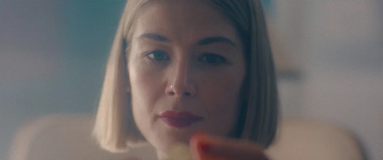 I Care A Lot (2020) movie still: closeup — A woman with blonde hair stands in a bright, out-of-focus indoor space. She looks into the lens while…