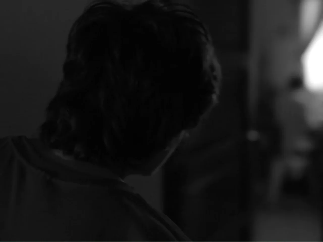 Güeros (2014) movie still: closeup — A dark indoor space with a silhouette against a bright light source. A young person with dark hair stands with…