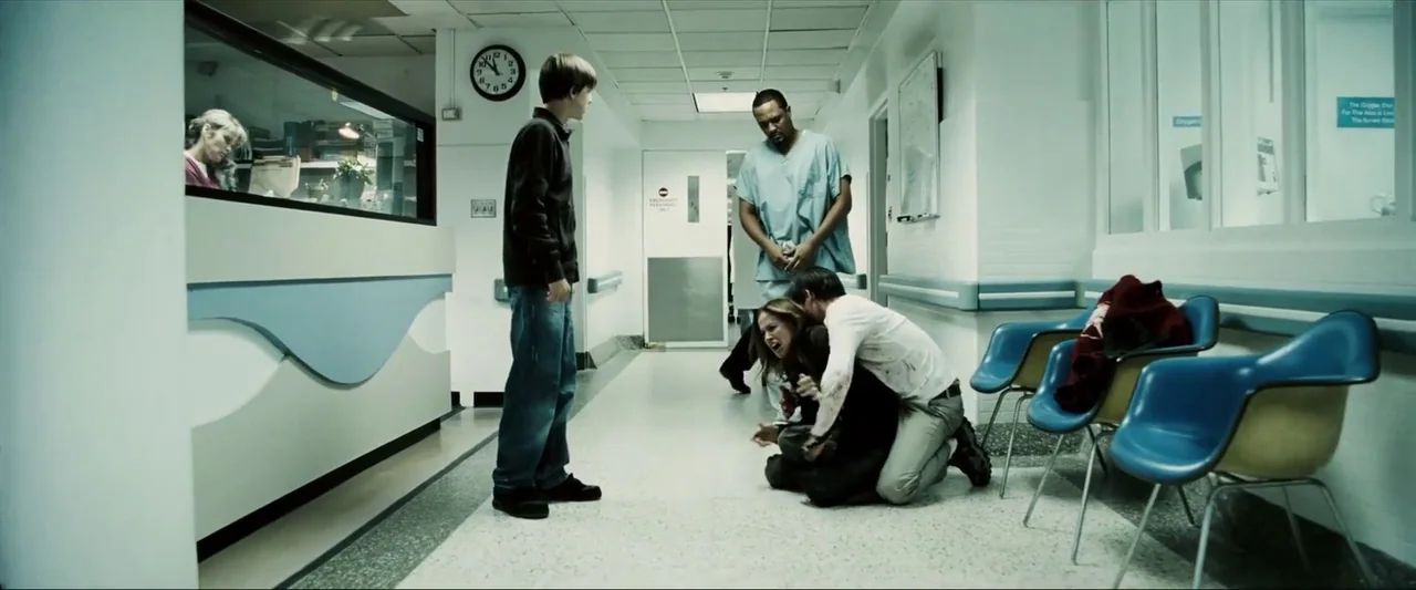 Death Sentence (2007) movie still: wide — A sterile hospital corridor features white walls, blue plastic chairs, and tile flooring. A group of…