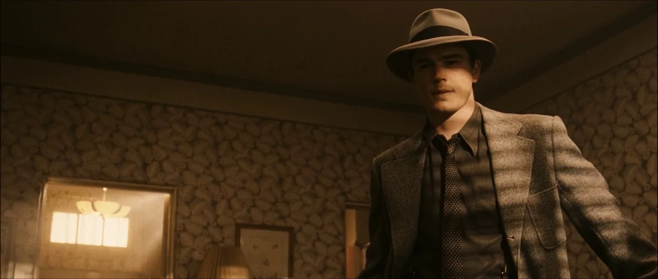 The Black Dahlia (2006) movie still: medium — A 1940s interior space features patterned wallpaper and venetian blind shadows on the wall. A man in a…