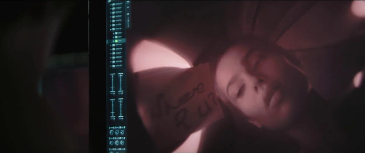 The Batman (2022) movie still: closeup — A digital screen displays a video recording of a woman with her eyes closed. A handwritten note with the…