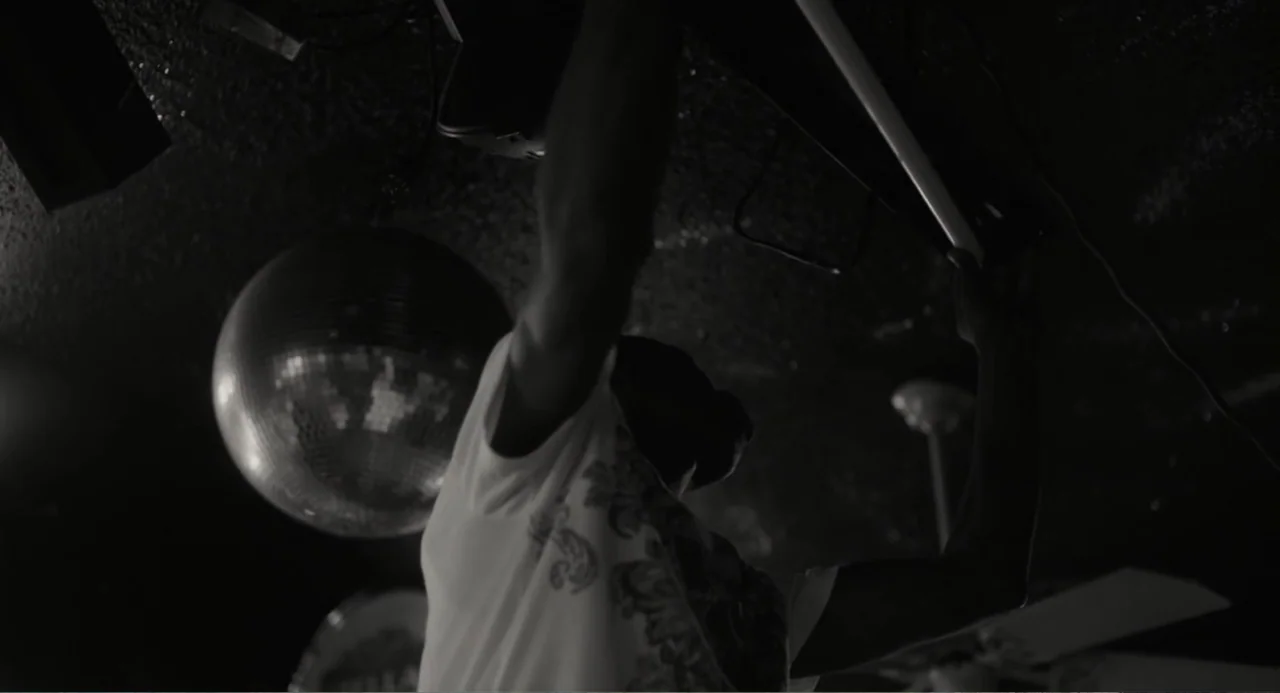What You Gonna Do When the World's on Fire? (2019) movie still: medium — A dimly lit room features a suspended disco ball and a dark ceiling. A…