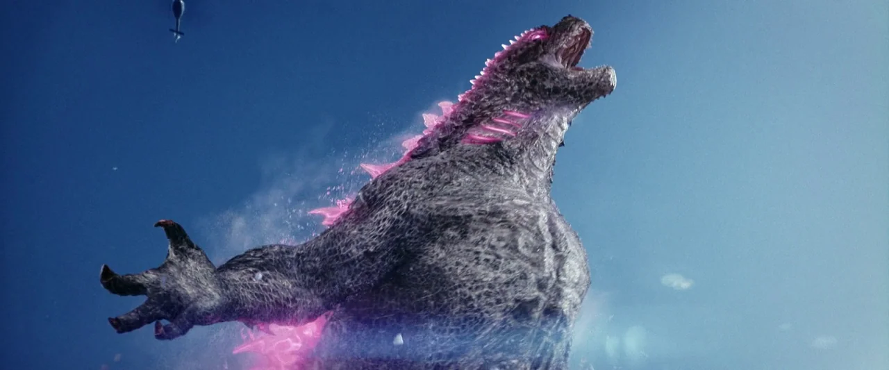 Godzilla x Kong: The New Empire (2024) movie still: fullbody — A gargantuan reptilian creature stands against a clear bright blue sky. It roars…