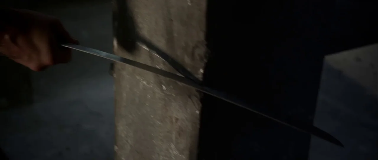 Universal Soldier: Day of Reckoning (2012) movie still: closeup — A close-up view shows a steel sword blade pressing against a textured wooden post.…