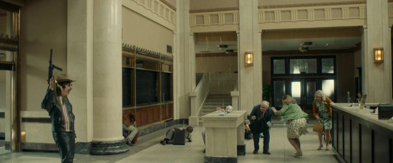 Stockholm (2019) movie still: wide — An opulent marble bank lobby with high ceilings and rows of service counters. Several patrons scramble toward…