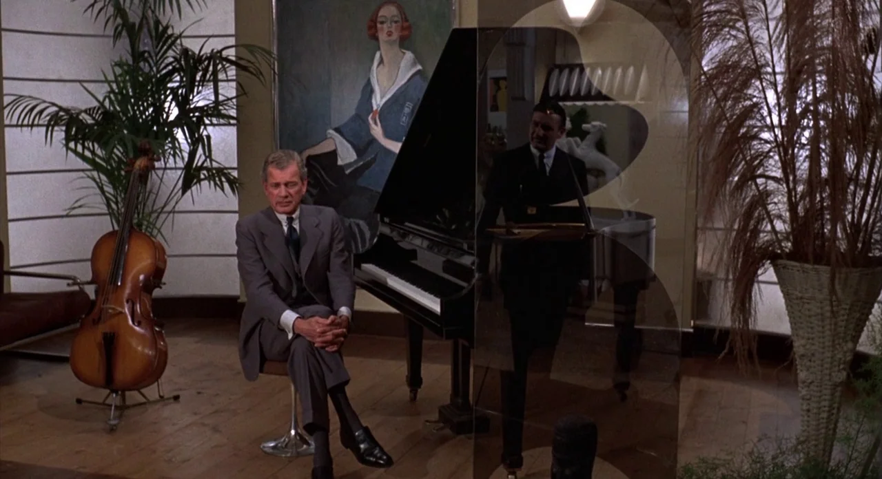 The Abominible Dr. Phibes (1972) movie still: medium — A room with wooden flooring contains a piano, a cello, and a large painting. An older man…