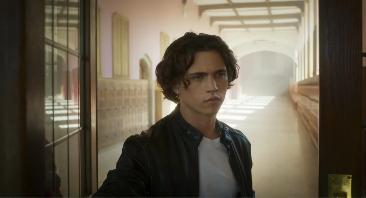 How to Date Billy Walsh (2024) movie still: medium — A sunlit school hallway features rows of wooden lockers and light-colored walls. A young man…