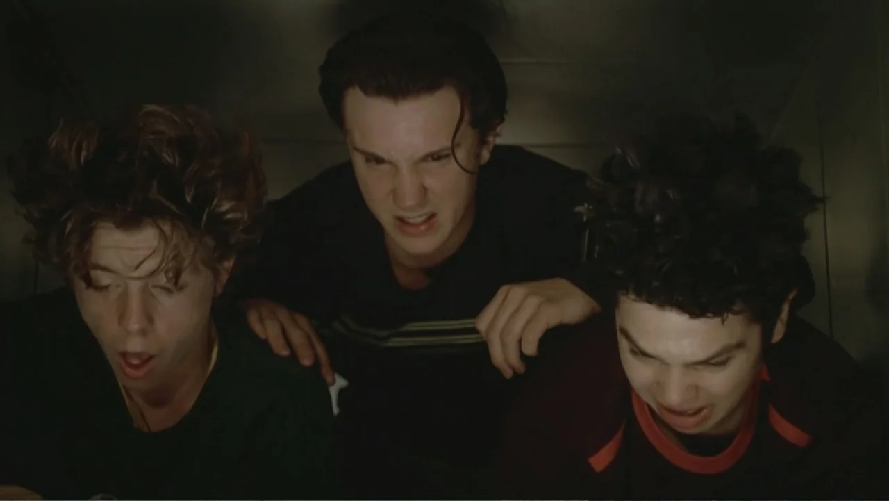 Not Another Teen Movie (2001) movie still: medium — Three teenage boys are tightly packed inside a dark, narrow enclosure. They look downward with…