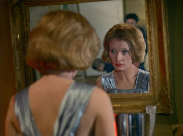 Satan’s Brew (1976) movie still: medium — A dimly lit room features a large ornate gold-framed mirror mounted on a wall. A woman with auburn hair…