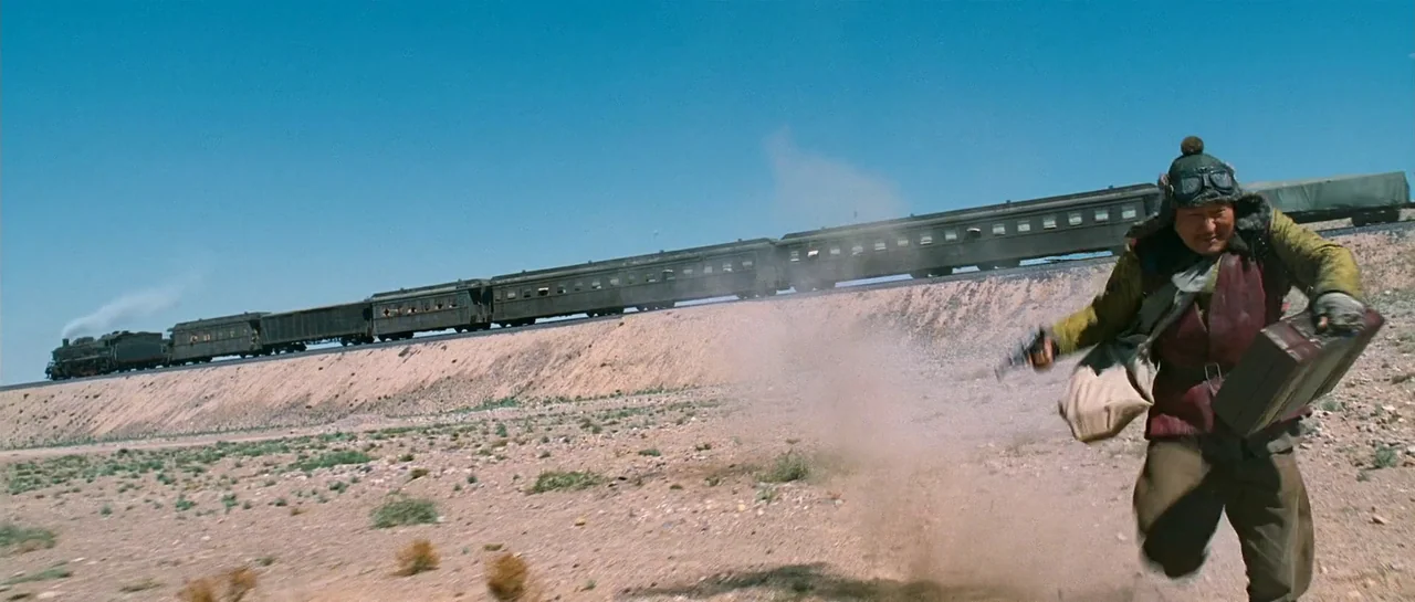 The Good The Bad The Weird (2008) movie still: fullbody — An arid, rocky desert landscape stretches out beneath a clear, bright blue sky. A man in…