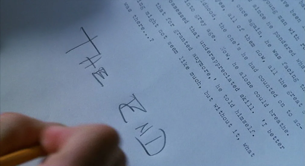 Misery (1990) movie still: closeup — A piece of white printer paper lies on a flat surface. The words THE END are written in dark ink near the…