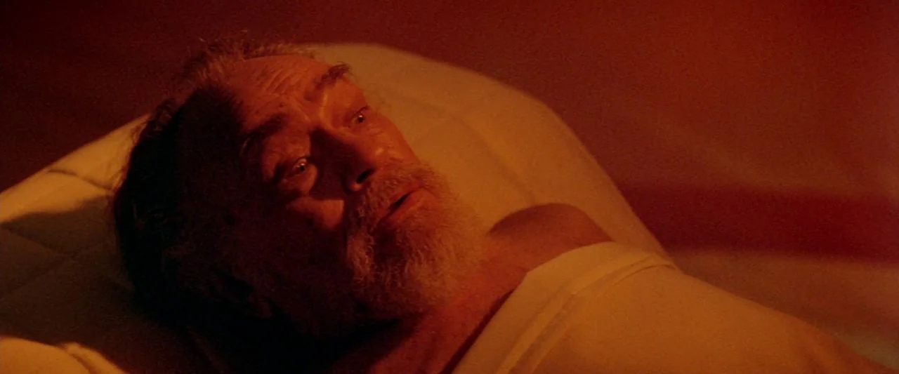 Soylent Green (1973) movie still: closeup — A man lies on a hospital bed in a dark room. The subject looks upward with a wide-eyed expression.