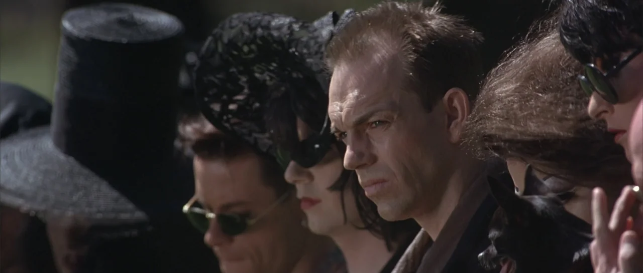 The Adventures of Priscilla, Queen of the Desert (1994) movie still: medium — A group of people wearing mourning attire stands outdoors in natural…