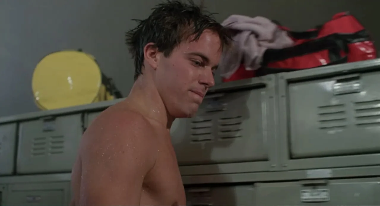 Dangerously Close (1986) movie still: medium — A locker room interior featuring rows of grey metal lockers and a red gym bag. A shirtless young man…