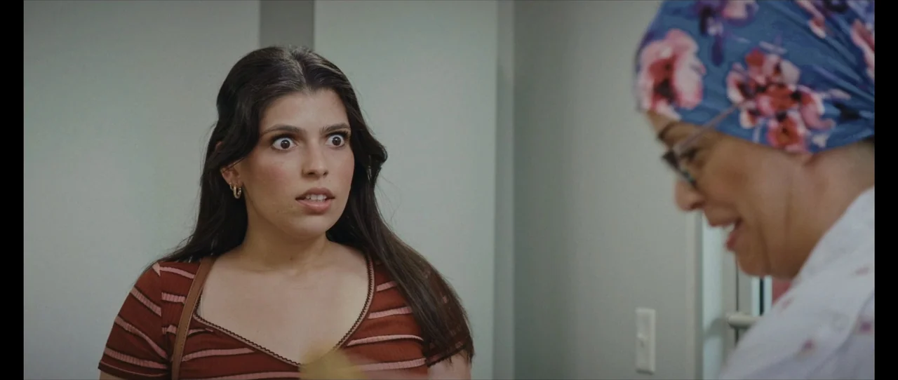 Ordinary Things (2001) movie still: medium — An interior medical space with pale gray walls serves as the backdrop. A young woman with wide eyes…