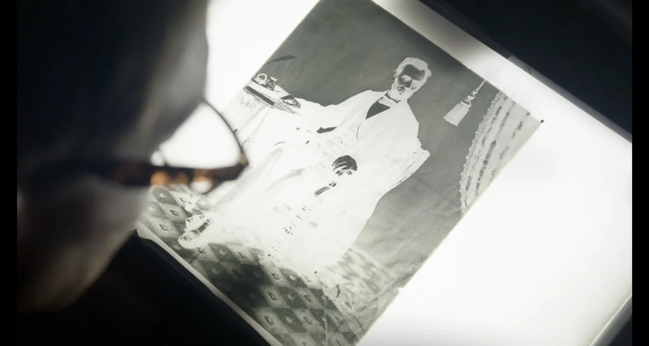 Living With Lincoln (2015) movie still: closeup — A person looks at a photographic negative of Abraham Lincoln on a bright light table. The sharp…