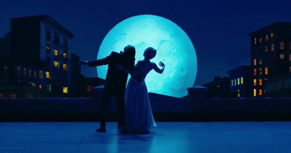 Joker: Folie à Deux (2024) movie still: fullbody — A flat rooftop overlooks a dark city with illuminated windows in the surrounding buildings. A man…