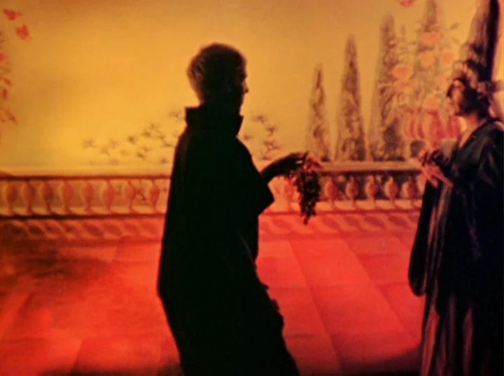 Inauguration of the Pleasure Dome (1954) movie still: medium — Two figures stand on a terrace against a painted scenic mural of cypress trees. One…