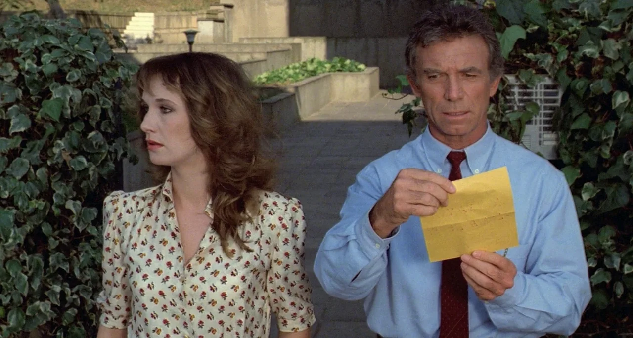Tenebre (1982) movie still: medium — A stone courtyard with climbing ivy walls and concrete stairs in the background. A man in a blue shirt inspects…