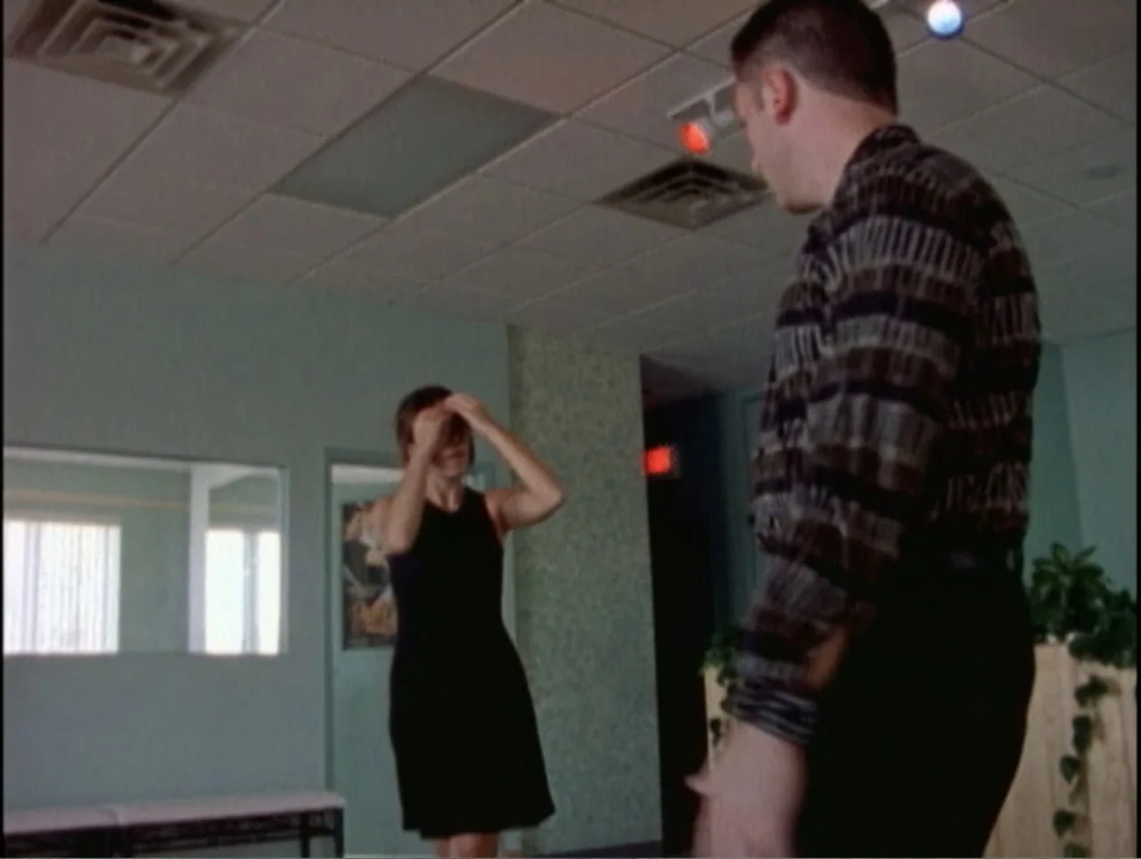America Undercover: Life Afterlife (2000) movie still: medium — A waiting room with teal walls features a drop ceiling and large mirror.