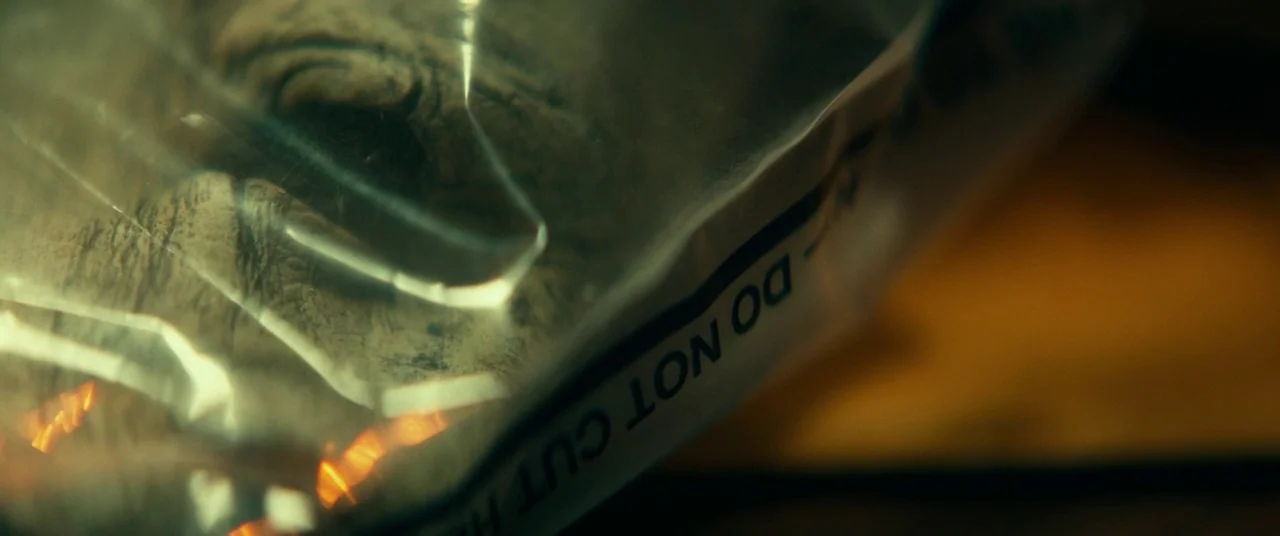 Halloween (2018) (2018) movie still: closeup — A close-up view of a clear plastic evidence bag with text printed on it. The bag is resting on a dark…