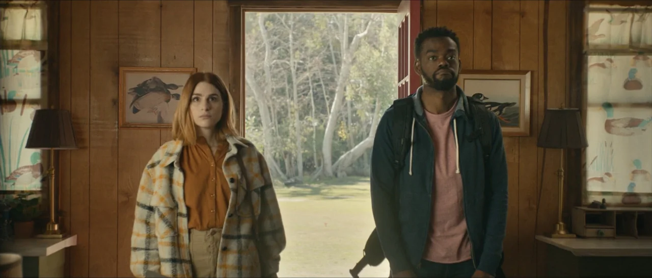 We Broke Up (2021) movie still: medium — A wooden cabin interior with knotty pine walls and decorative waterfowl artwork on walls. A man and a woman…