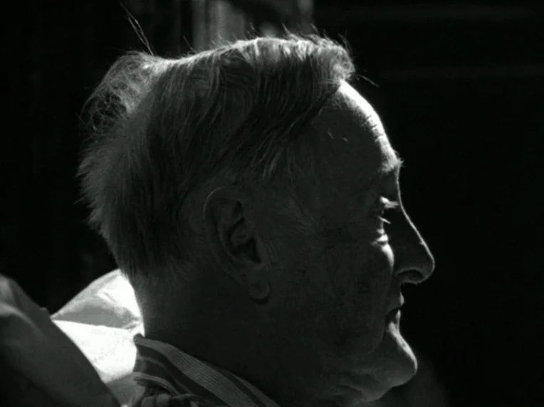 Death and Transfiguration (1983) movie still: closeup — An elderly man in profile is lit against a dark, featureless background. He sits in shadow…