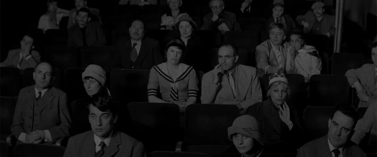Jules and Jim (1962) movie still: medium — A crowded movie theater interior with rows of plush seats occupied by diverse individuals. The audience…