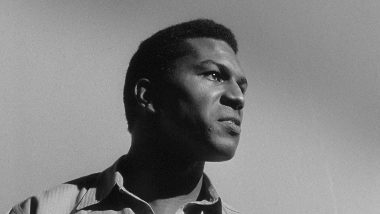 Shock Corridor (1963) movie still: closeup — An outdoor setting under direct sunlight with an empty sky background. A man looks off-camera while…