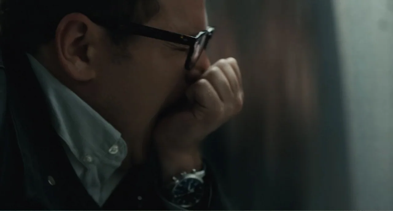 Bad Boys: A True Story (2003) movie still: closeup — A man in a dark jacket stands indoors near a window during the day. He holds his hand over his…