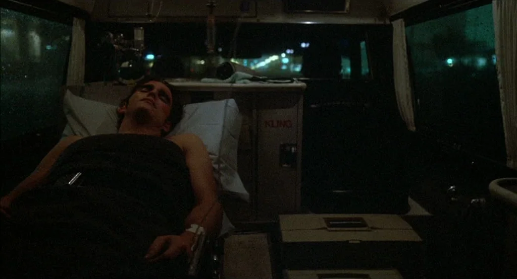 Drugstore Cowboy (1989) movie still: medium — The cramped interior of an ambulance at night features medical equipment and dark surfaces. A young…