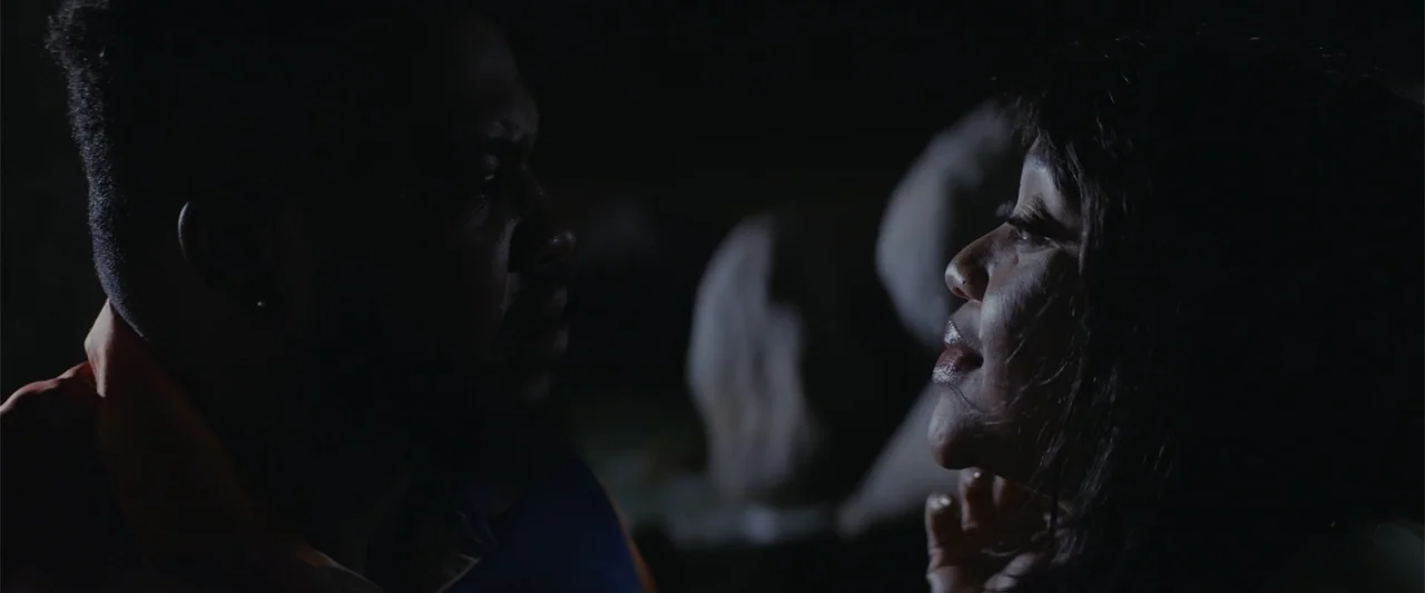 A Scam Called Love (2025) movie still: medium — A dark outdoor space at night with two people facing each other closely. A man and woman are…