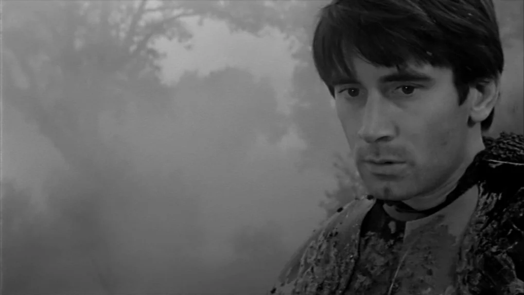 Falstaff (Chimes at Midnight) (1965) movie still: closeup — A dense, foggy woodland environment with obscured trees in the background. A young man…